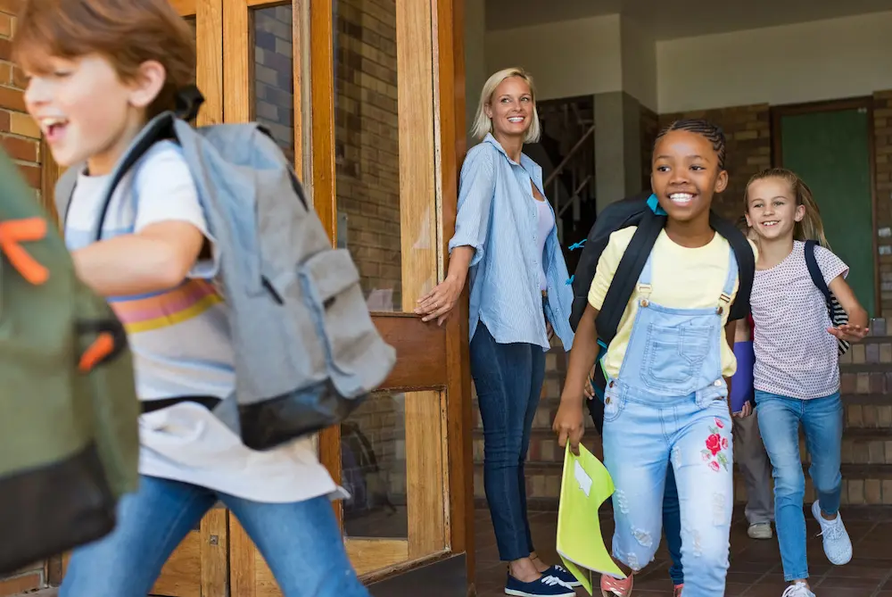 Grundschulkinder laufen aus der Schule und lachen